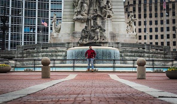 Man in red plaid shirt stands in front of a historic monument at Monument Circle.