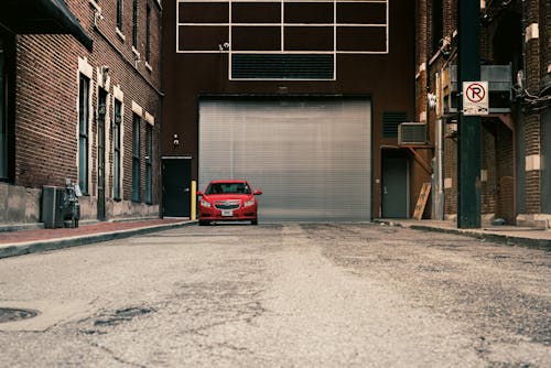 Red Car Parked near Brick Building