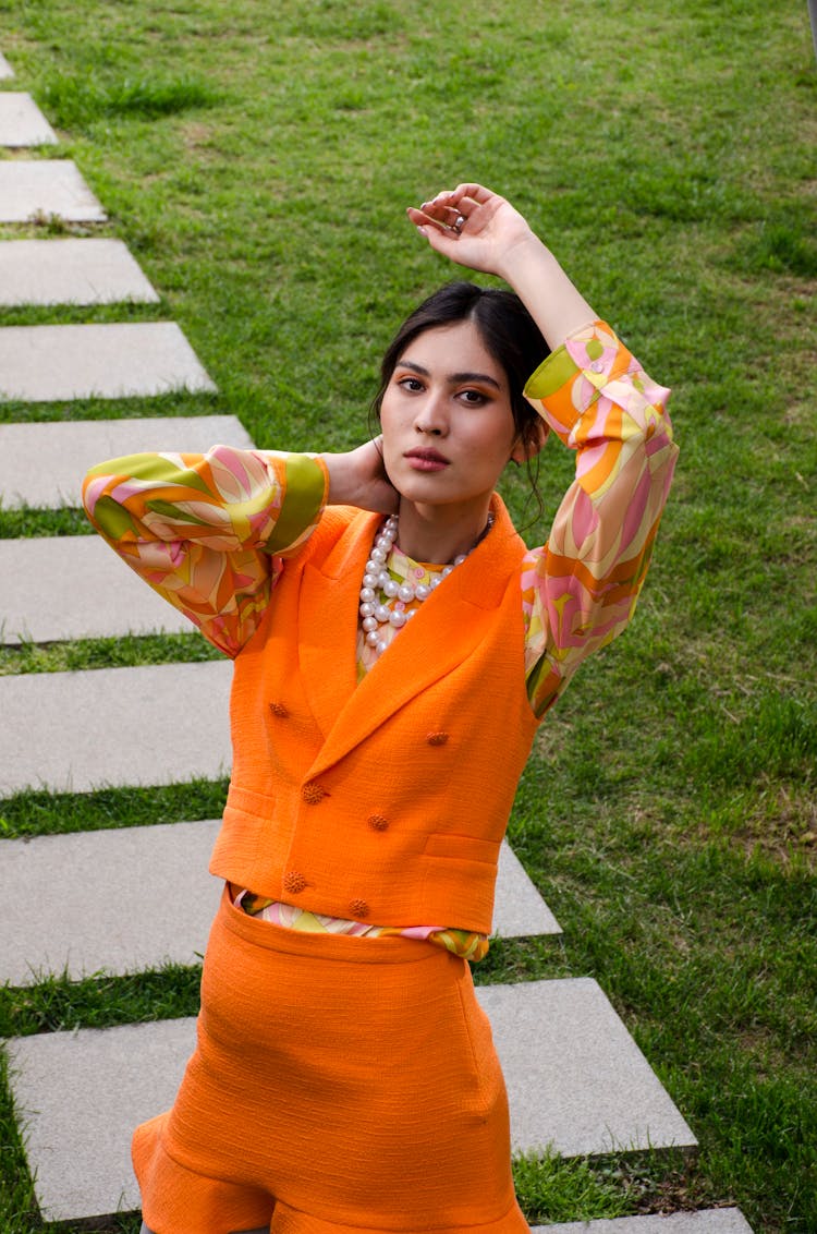 Beautiful Woman In Orange Clothes On Green Grass