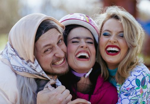 Three friends laughing joyfully outdoors, capturing happy moments together.