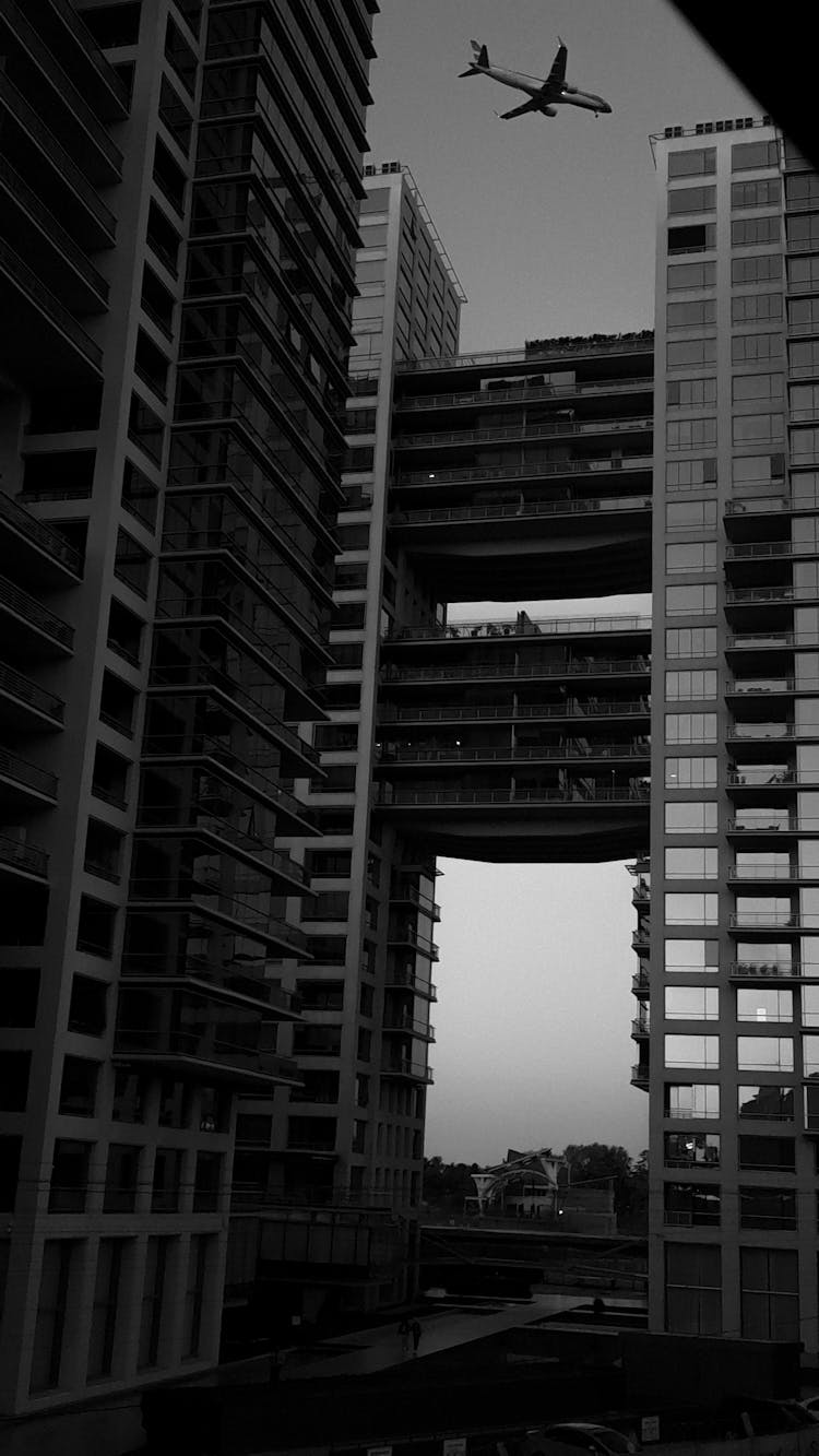 Grayscale Photo Of An Airplane Above A Building