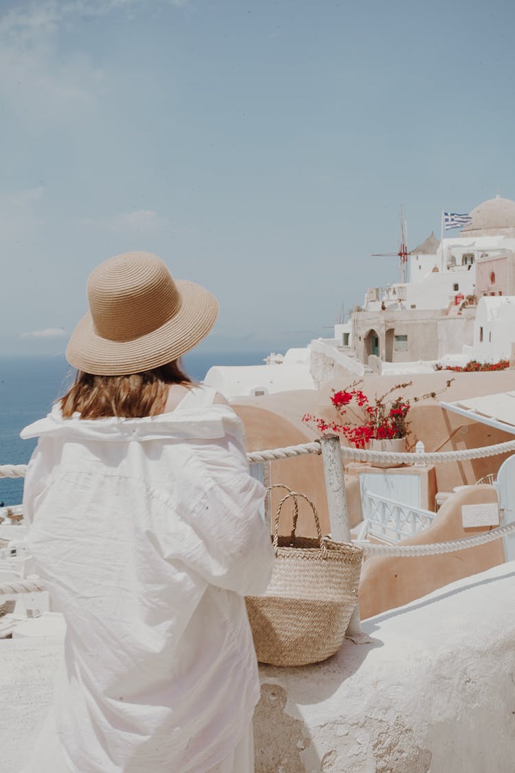 Woman Standing And Looking At A View Of Coastal Town In Greece