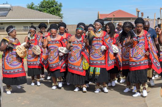 A vibrant depiction of a traditional African festival with women in colorful costumes, celebrating their culture outdoors.