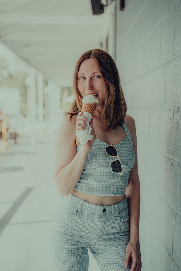 A Woman In Blue Top Eating An Ice Cream