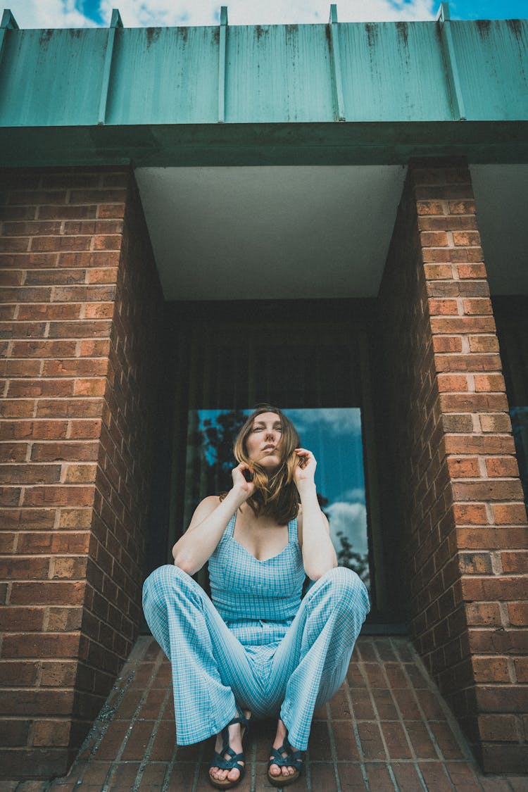 Woman Sitting Between Building Walls