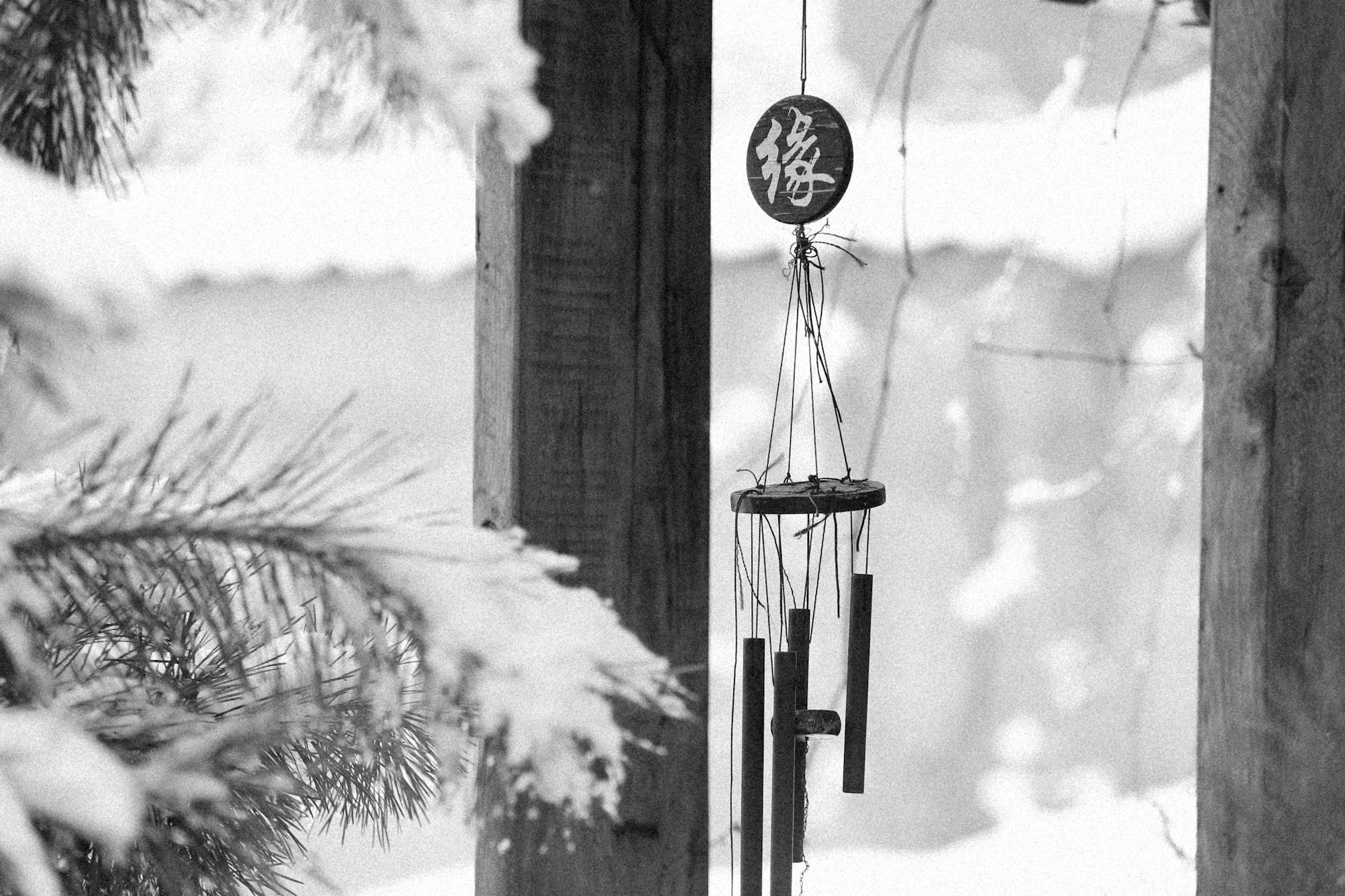 Serene black and white winter scene featuring a hanging wind chime outdoors.