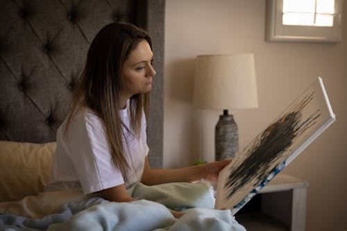 Woman Looking at a Painting while on the bed