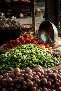 Colorful assortment of fresh vegetables at an outdoor market stall, showcasing tomatoes, peppers, and other produce.