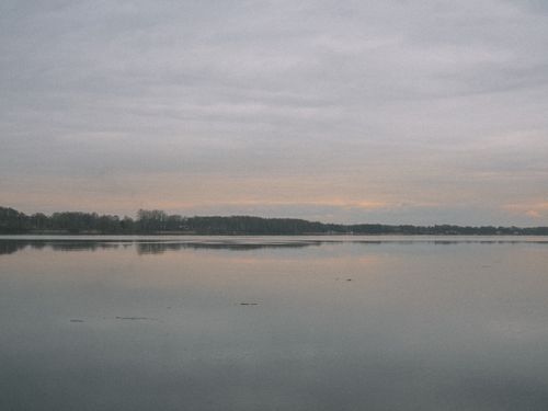 Free Tranquil lake scene with gentle reflections of sky and trees at dusk, offering a peaceful nature view. Stock Photo
