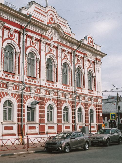 Free Neoclassical architecture facade of a city building with parked cars in an urban setting. Stock Photo