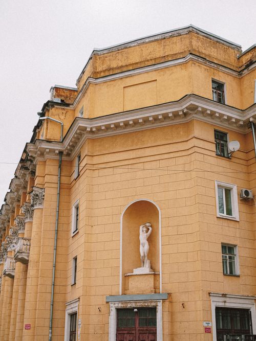 Free Elegant yellow facade featuring a classic statue in an urban setting. Stock Photo