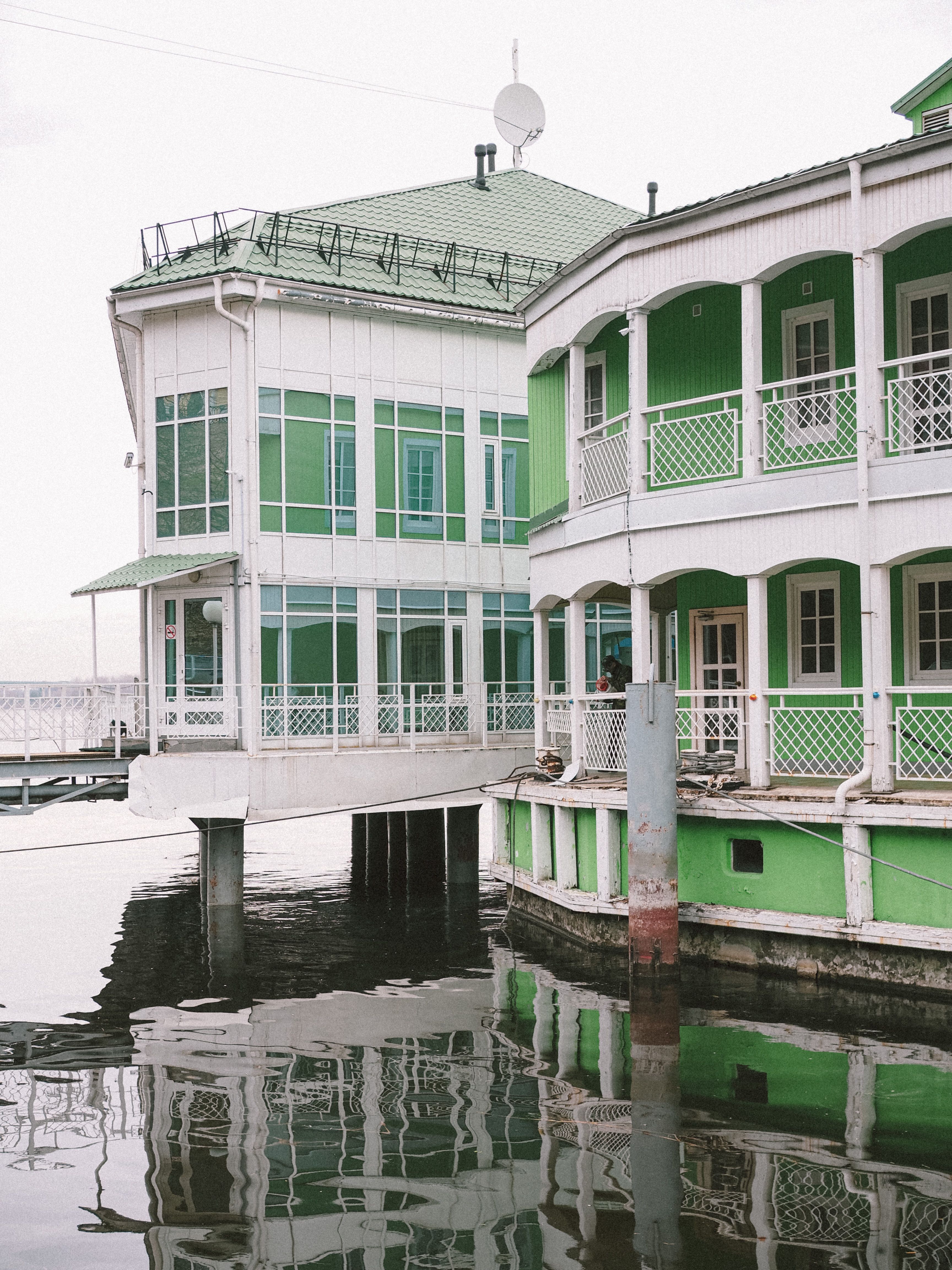 A picturesque green building with balconies reflecting in a calm river, ideal for travel and architecture themes.