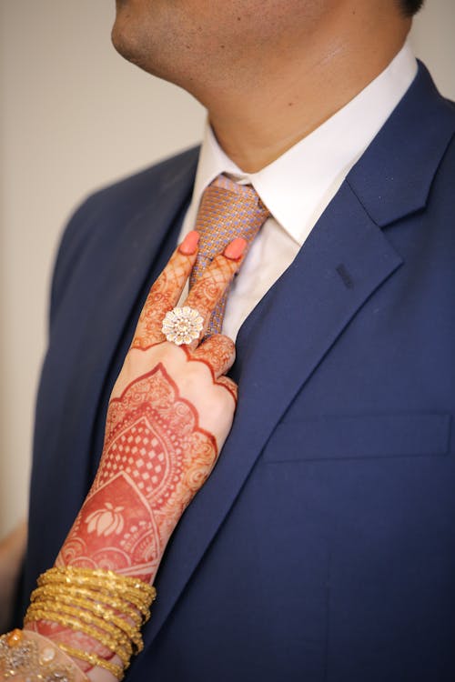 A Woman's Hand With Tattoo Touching a Man's Necktie