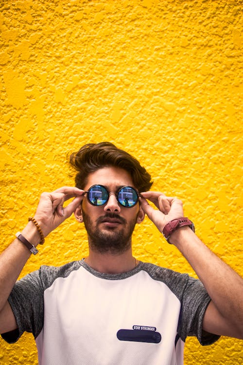 Hombre De Camisa Blanca Y Gris Con Gafas De Sol Contra La Pared Amarilla