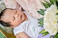 Baby in White Shirt Lying on White Flower Bouquet