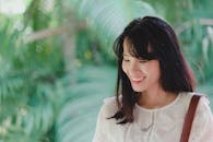 一名年轻女子在郁郁葱葱的绿叶前笑容满面