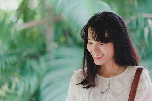 一名年轻女子在郁郁葱葱的绿叶前笑容满面