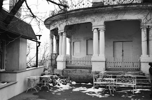 Grayscale Photo of Concrete Building With Wooden Fence