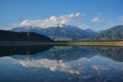 Majestic mountains mirrored on a tranquil lake under a bright blue sky, ideal for nature lovers.
