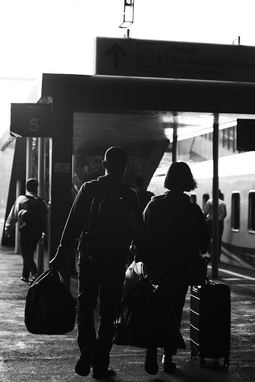 Grayscale Photo of People Carrying Their Luggage