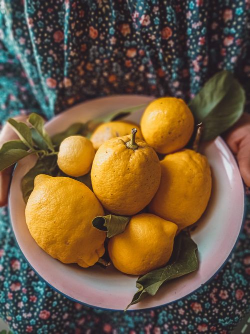 Free Freshly picked lemons displayed in a bowl with green leaves, showcasing vibrant citrus colors. Stock Photo