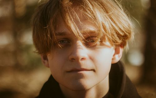 Free Close-up of a young blonde man with soft lighting, outdoors in natural setting. Stock Photo
