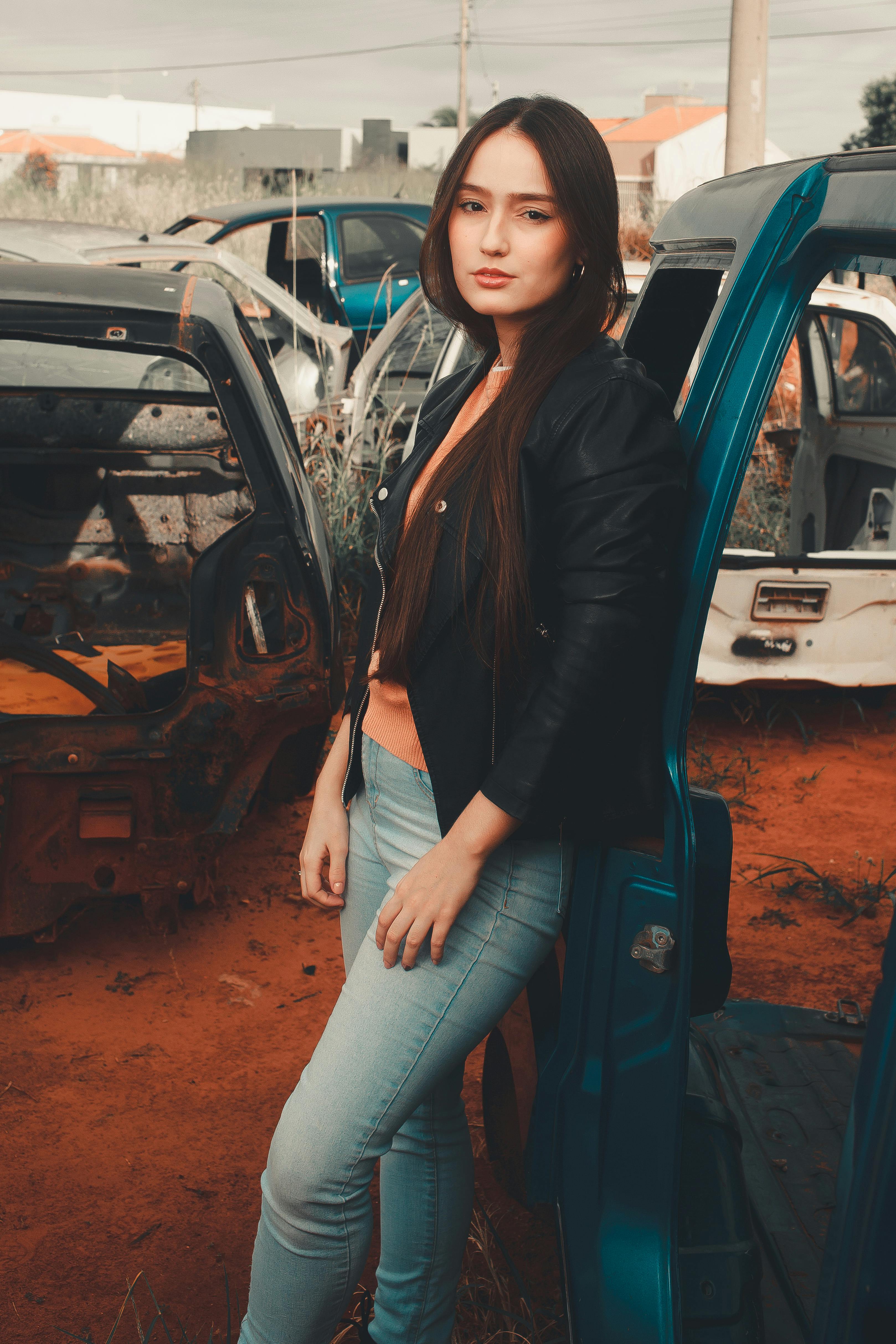 Download A Woman In A Black Jacket Standing In Front Of A Car Wallpaper