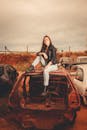 Woman in Black Jacket Sitting on Car Hood