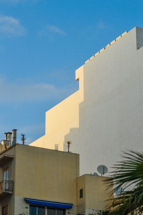 Free Modern urban architecture casting geometric shadows under clear blue skies. Stock Photo