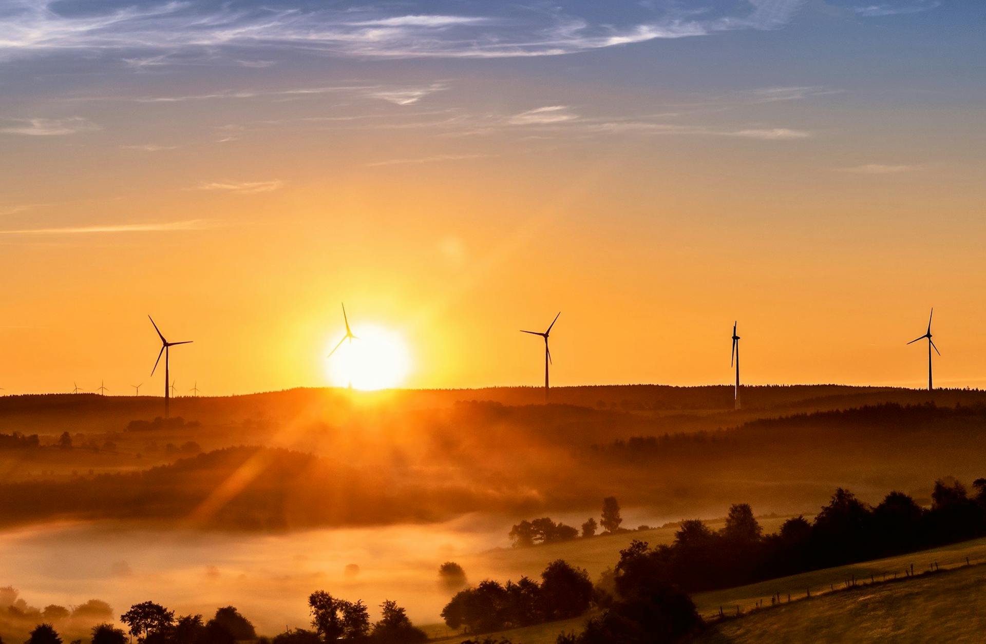 Breathtaking sunrise view with wind turbines on a foggy landscape, symbolizing renewable energy and sustainability.