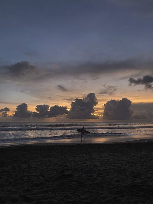 Silhouette of a Surfer Standing on the Beach