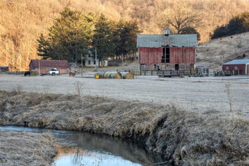 Free A scenic view of a rural farm with barns, hay bales, and a creek in Minnesota. Stock Photo