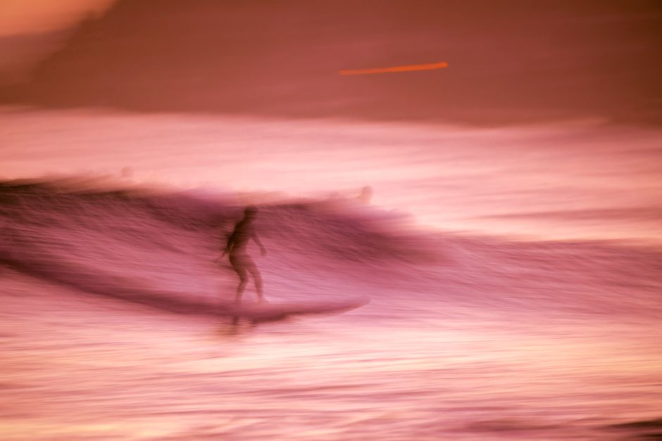 Artistic shot of a surfer riding waves at sunset in Yangyang, South Korea.