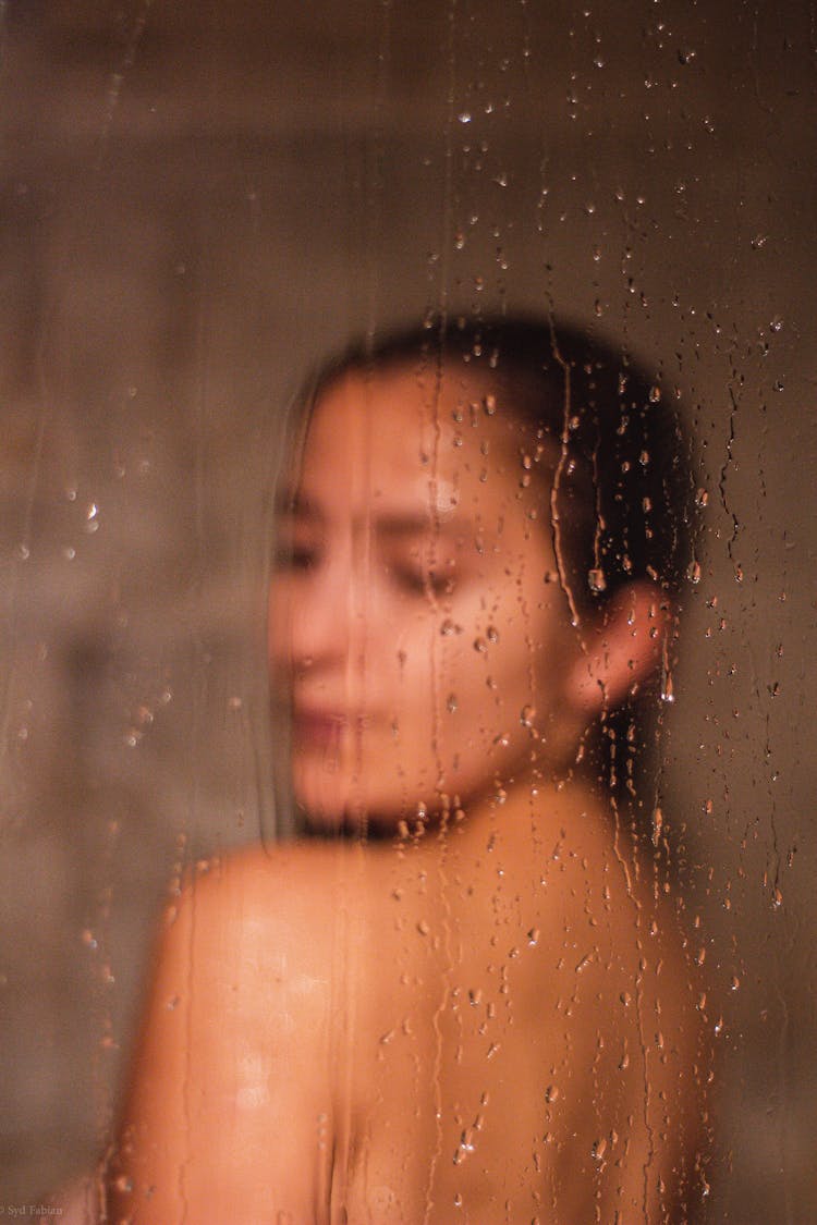 Woman Taking Shower Seen Through Glass