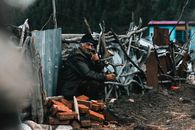 Man in Black Jacket Sitting on Brown Wooden Fence