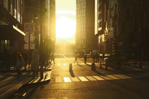 Free A vibrant sunset casts warm light over a bustling Moscow street with pedestrians and modern architecture. Stock Photo