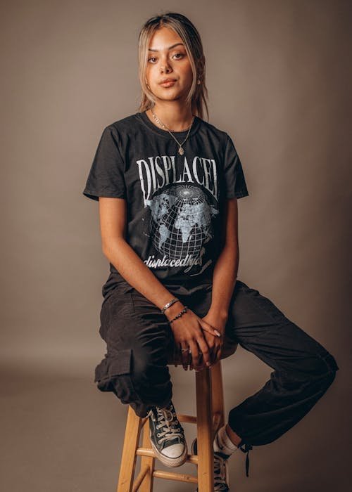 Woman in Black Shirt and Black Pants Sitting on Wooden Chair