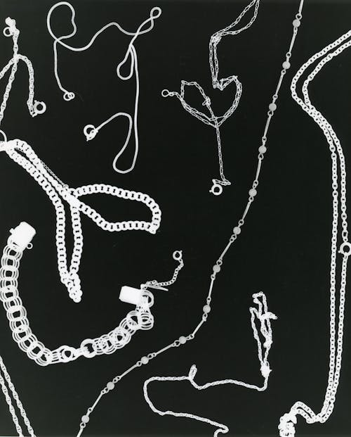Close-Up Shot of Silver Necklaces on Black Surface