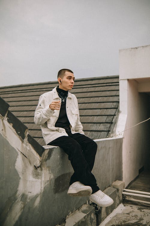 Man Sitting on Concrete Fence