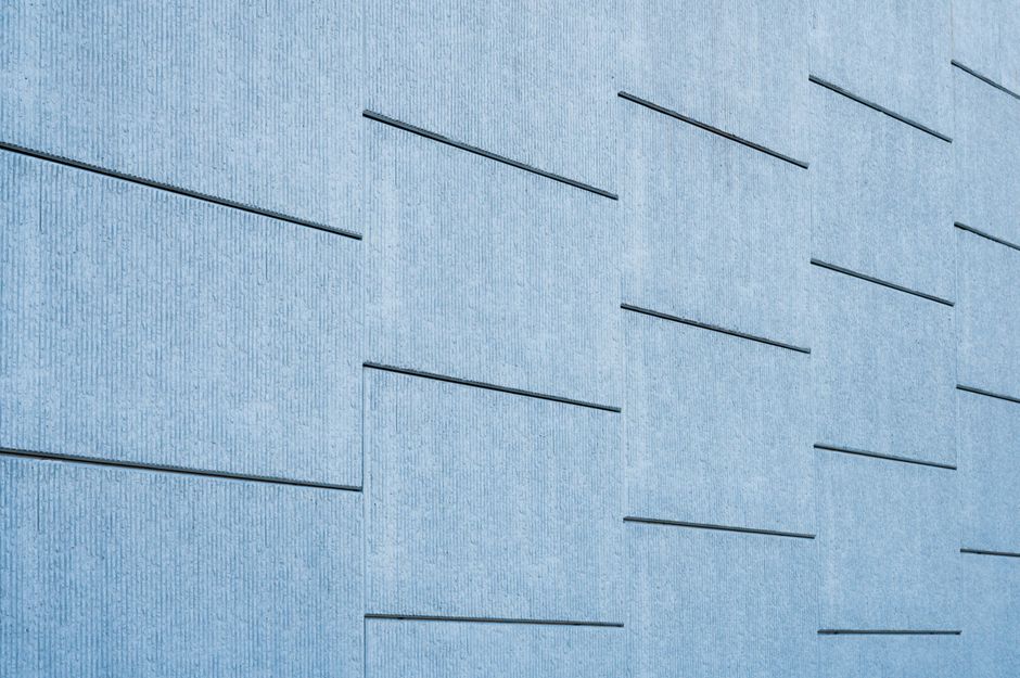 Blue tinted concrete wall featuring sleek geometric lines and modern architecture.