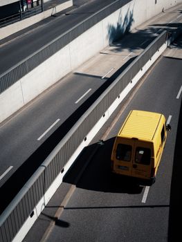 Aerial view of a yellow van on an empty city highway, showcasing urban infrastructure and transportation.