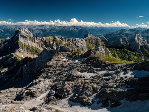 Free Breathtaking view of rugged mountains under a clear blue sky with fluffy white clouds. Stock Photo
