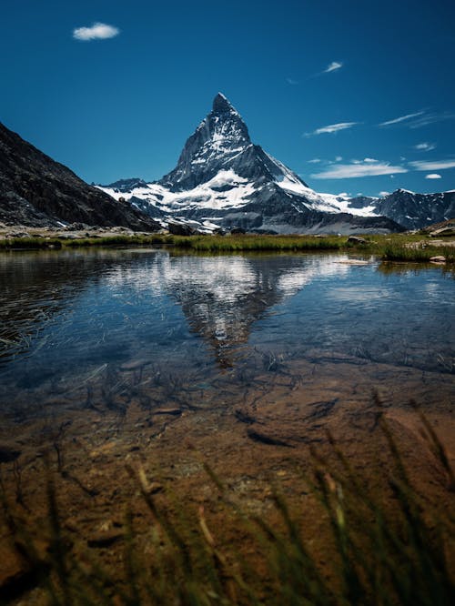 Free Snow Capped Rocky Mountain Reflecting in Crystal Clear Water Stock Photo