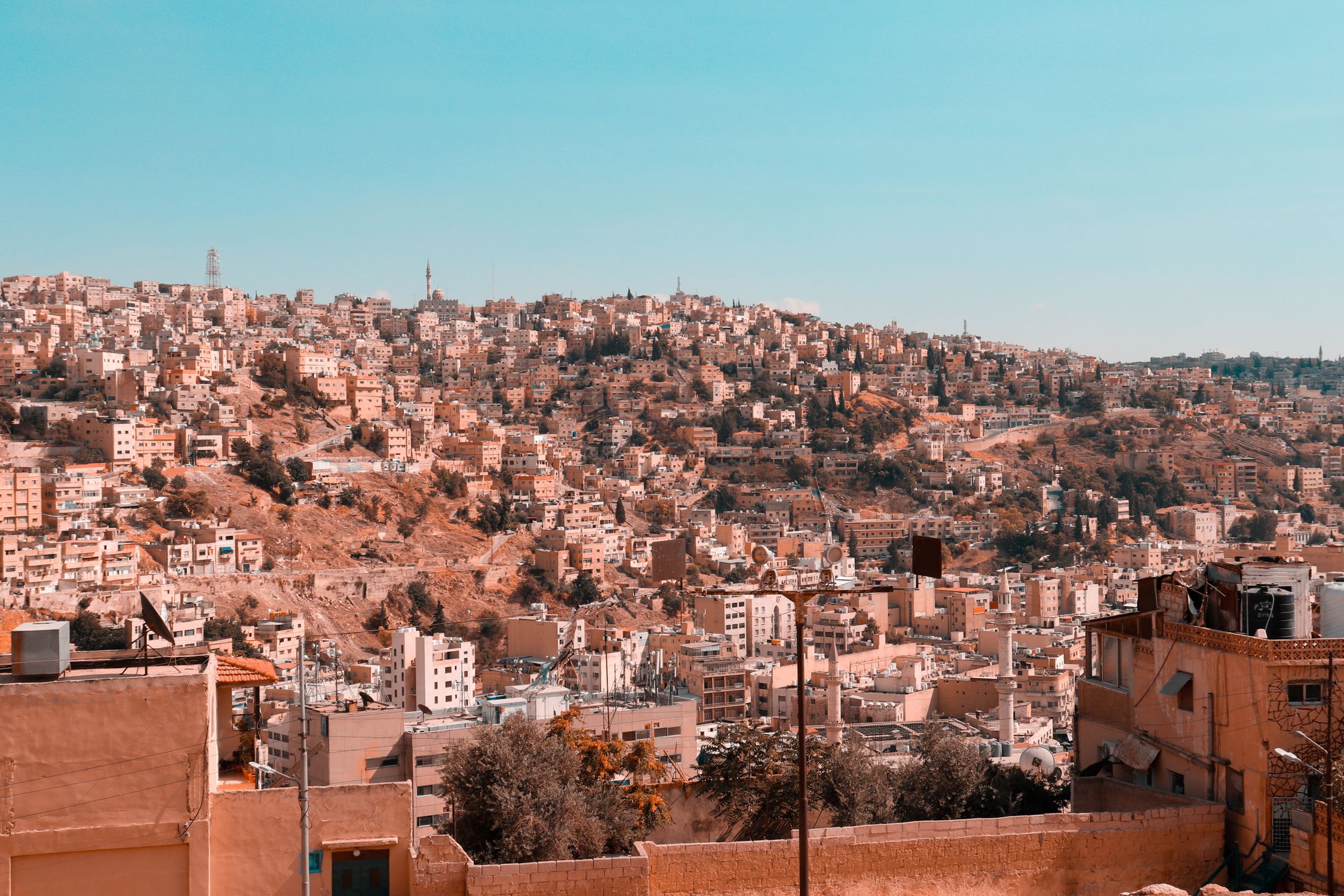 Sweeping view of Amman's hillside cityscape capturing a blend of modern and traditional architecture under a blue sky.