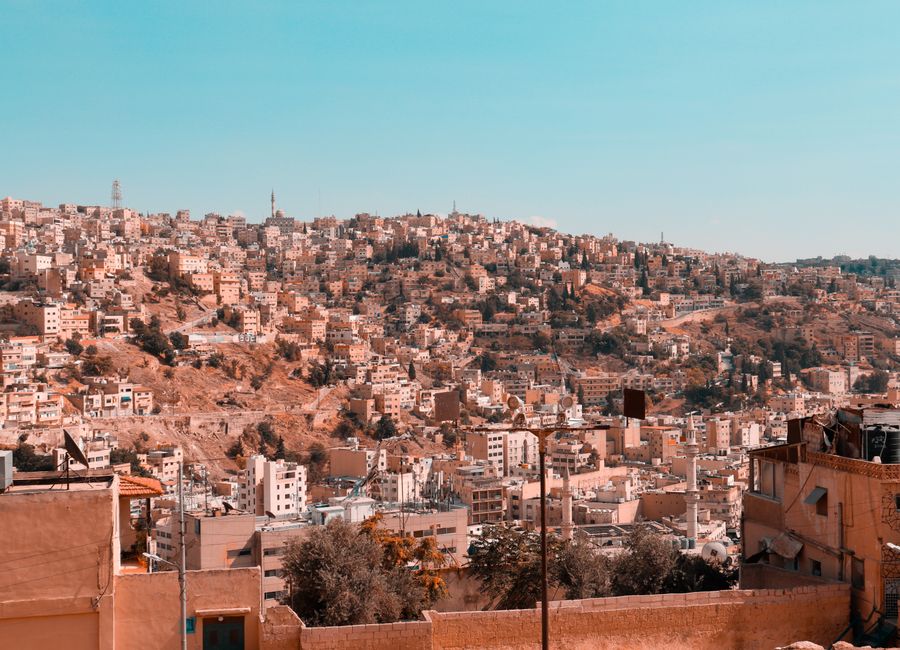 Sweeping view of Amman's hillside cityscape capturing a blend of modern and traditional architecture under a blue sky.