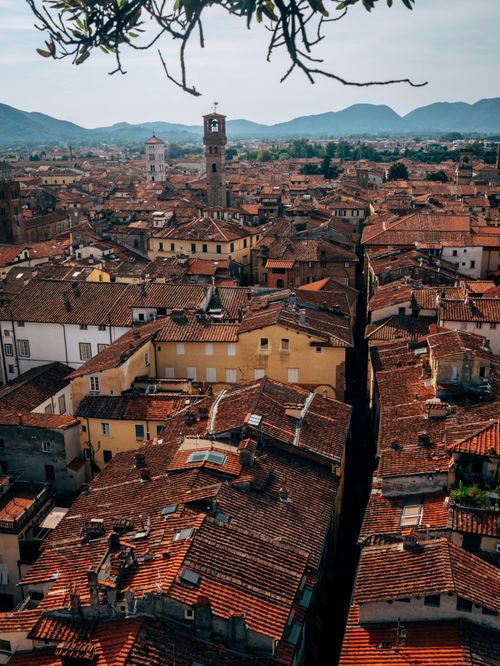 Free Aerial view showcasing the rustic charm of an old Italian town with terracotta roofs and distant mountains. Stock Photo