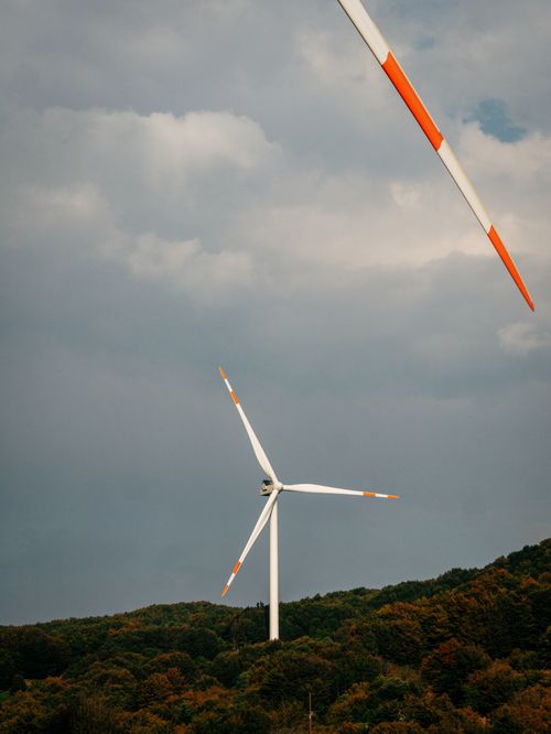 Free Vertical shot of wind turbines on a hillside under a cloudy sky, promoting renewable energy. Stock Photo