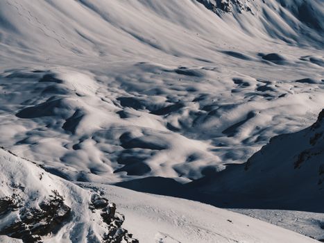 A stunning view of snow-covered mountains with rolling terrain under sunlight.
