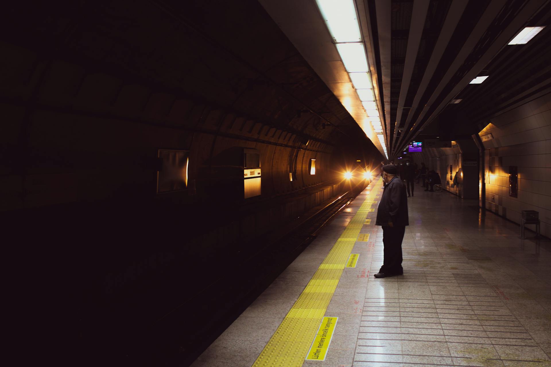 Man in Black Jacket Standing Behind the Yellow Line while Waiting for the Train