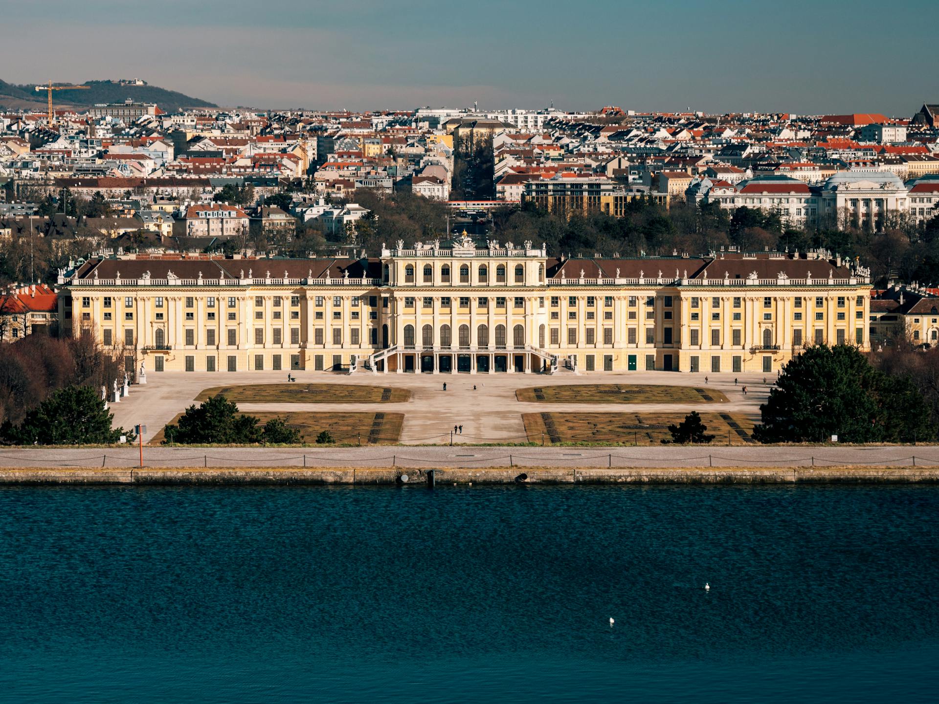 Stunning aerial shot of Schönbrunn Palace with Vienna cityscape in the background.